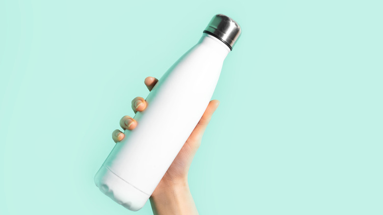 woman's hand holding water bottle
