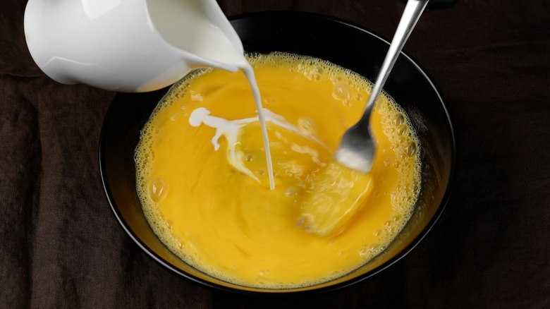 pouring milk into whisked eggs