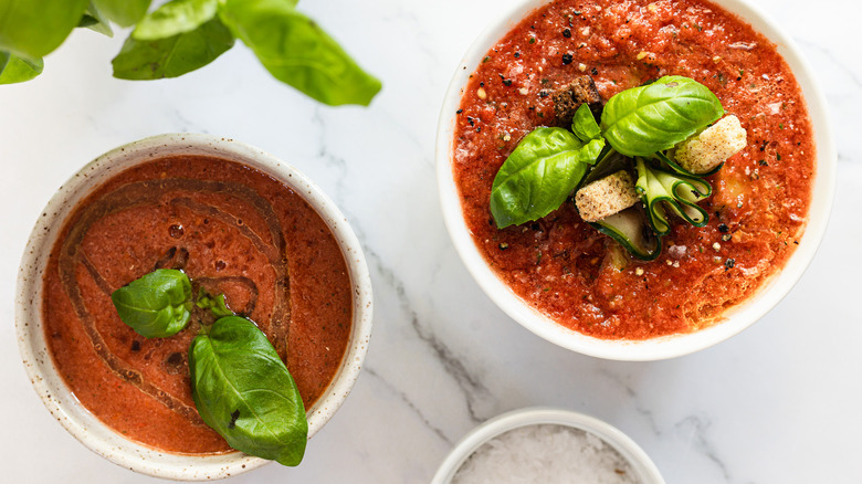 Two bowls of soup with salt and basil