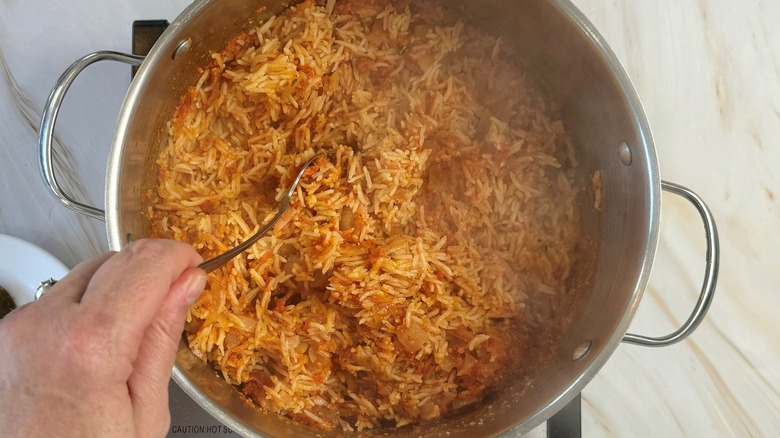 hand stirring rice in pot