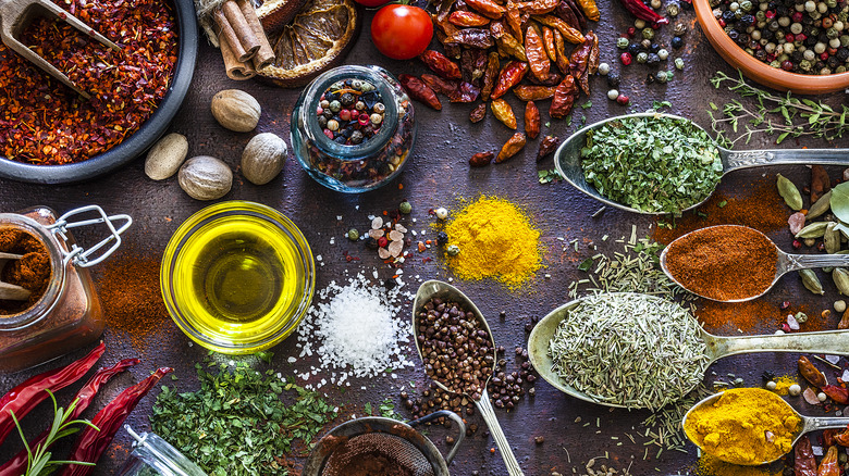 a mixture of spices and herbs in spoons and jars on a black background