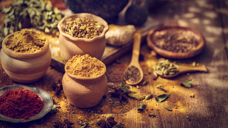 whole and ground spices on a wooden table in clay jars