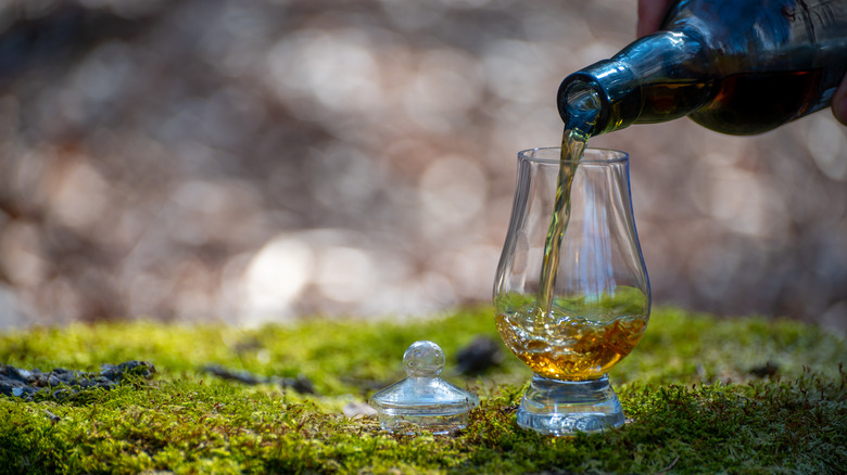 Pouring a glass of whisky on peat