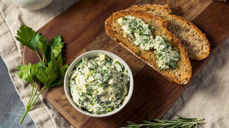A bowl of herb butter with slices of bread