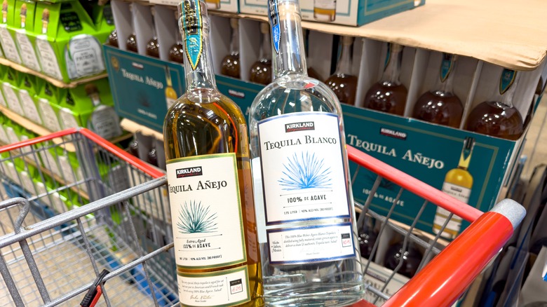 A bottle of Kirkland Signature Añejo and Kirkland Signature Blanco Tequila in a shopping cart at Costco