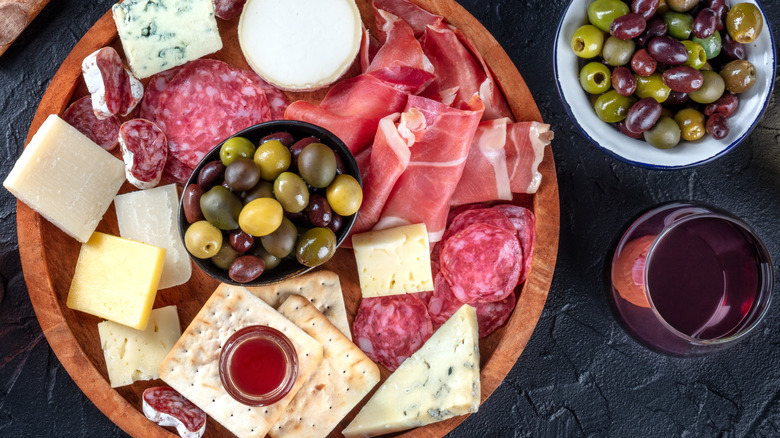 diverse spread of meats, cheeses, and olive with glasses of wine