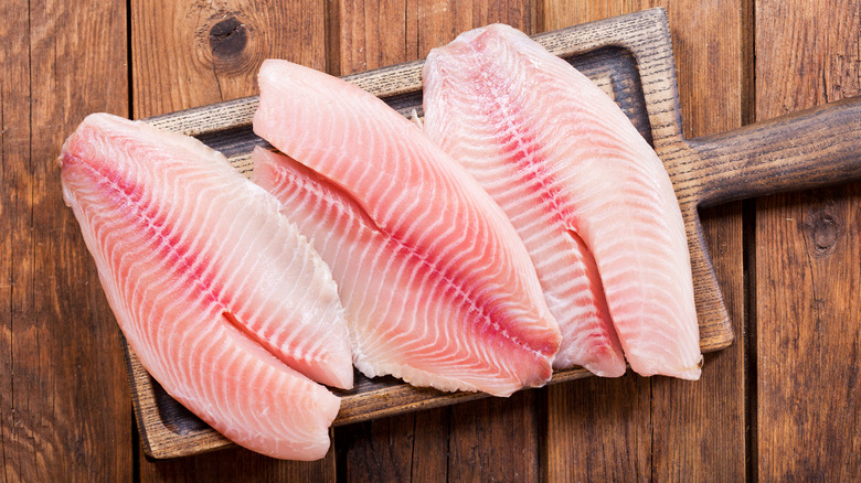 Fresh raw white fish filets on wooden cutting board