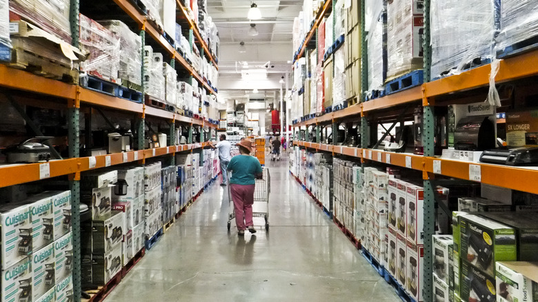 A Costco shopper pushing a cart and perusing the aisles.