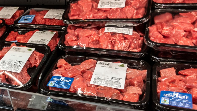 A refrigerator case full of packaged stew meats.