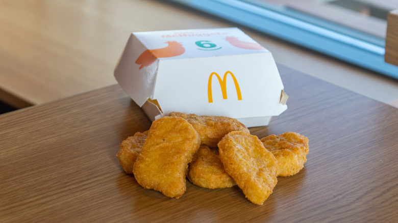 McDonald's McNuggets with their box behind them on a wooden table