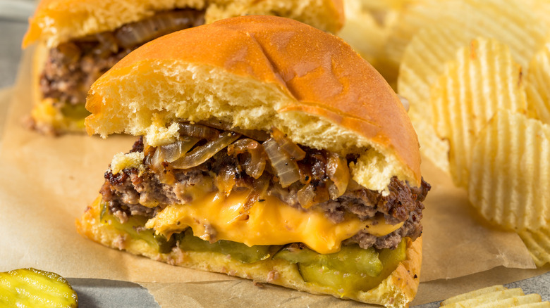 Half of a Juicy Lucy cheeseburger with potato chips in the background