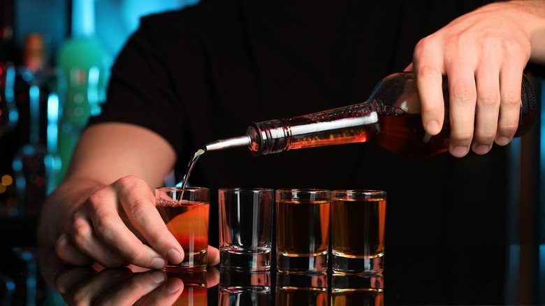 Bartender pouring alcohol into shot glasses