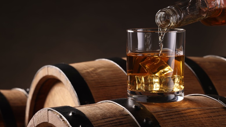 Glass of whiskey on wooden barrels