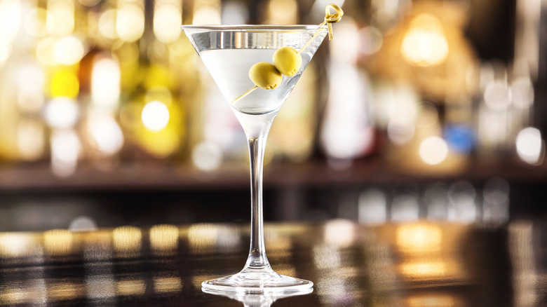 Dry martini cocktail garnished with olives on a bar