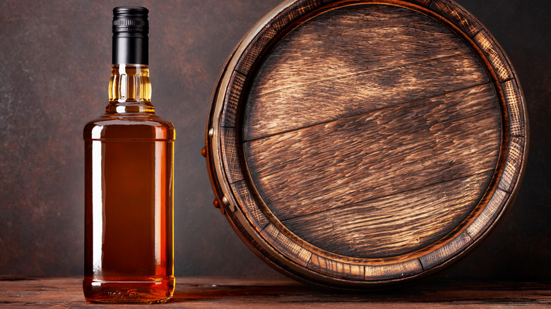 Whiskey bottle next to barrel