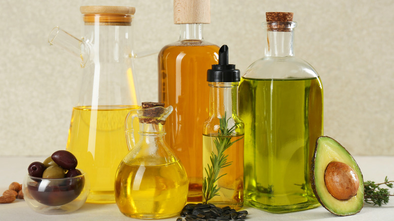 Different cooking oils in bottles are arranged in front of a neutral background.