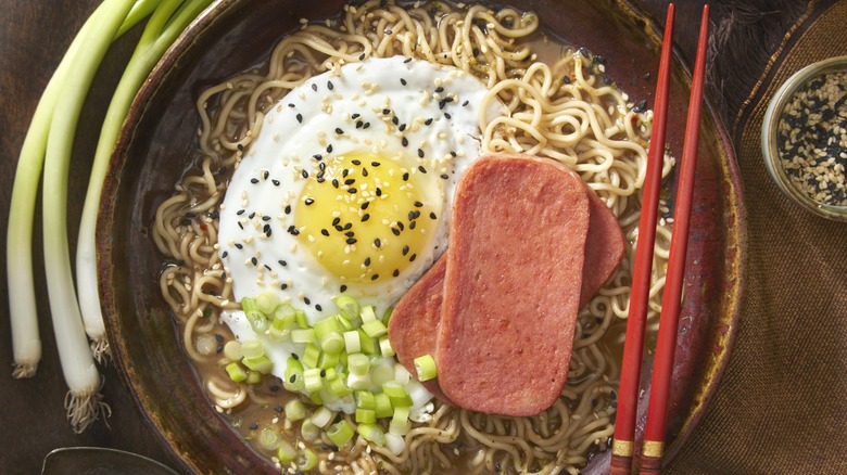 Ramen soup with SPAM and fried egg shown with chopsticks