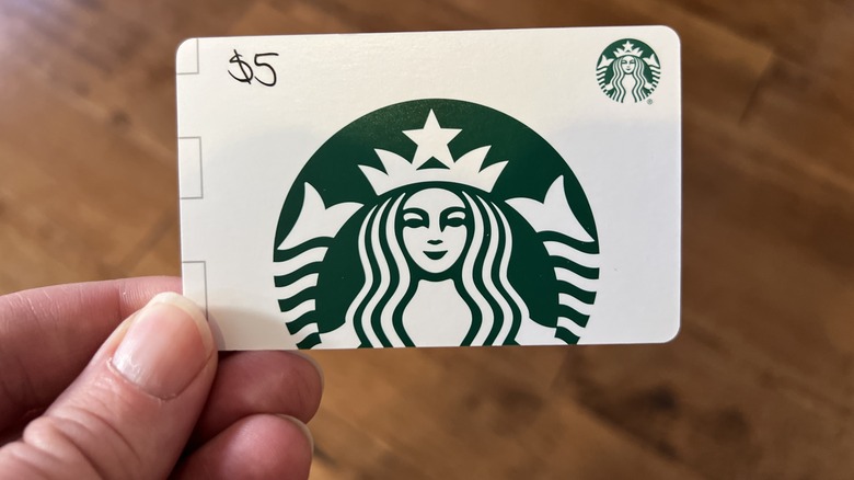 Regular Starbucks gift card held between fingers