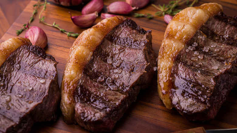 Three grilled picanha steaks with visible fat cap, seasoned with coarse salt