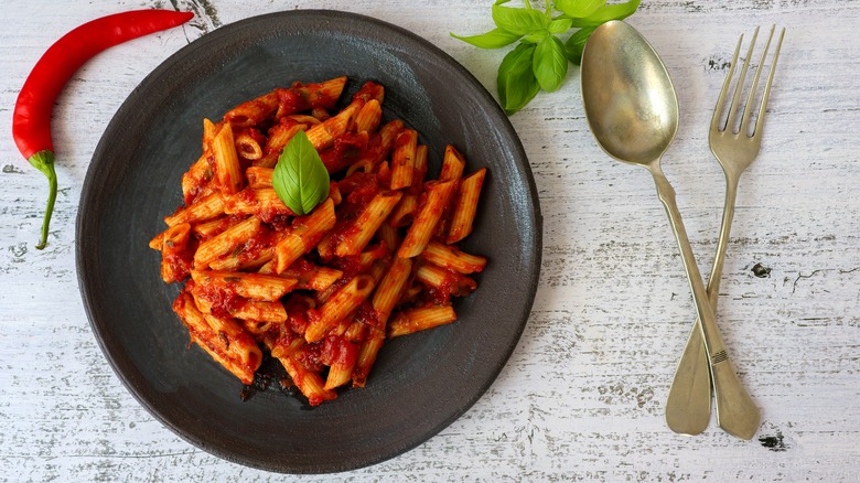 Plate of penne arrabbiata with pepper and cutlery