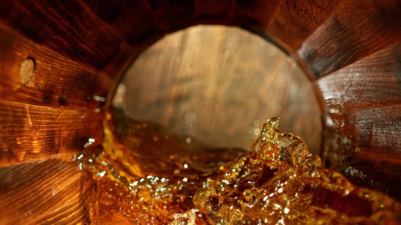 splashing whiskey in wooden barrel