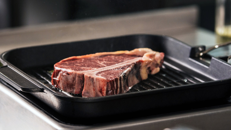 T-bone steak cooking in a griddle pan