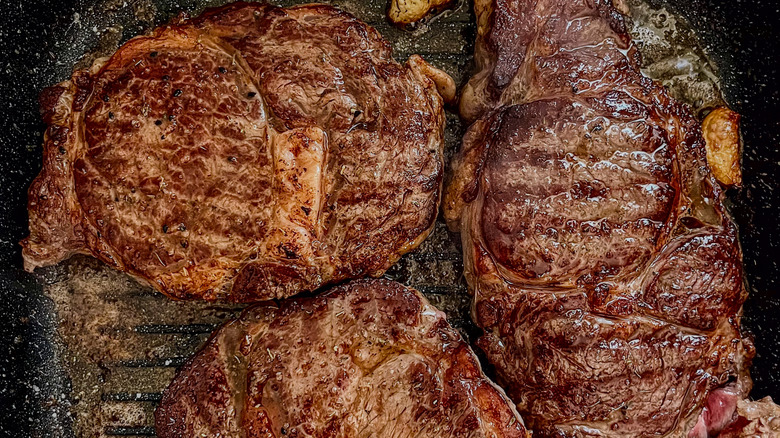 Multiple steaks cooking in a griddle pan