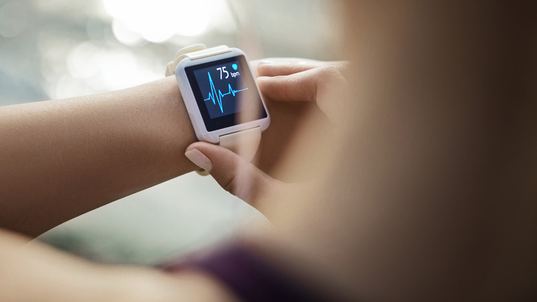 Woman checks her heartbeat on wrist monitor screen