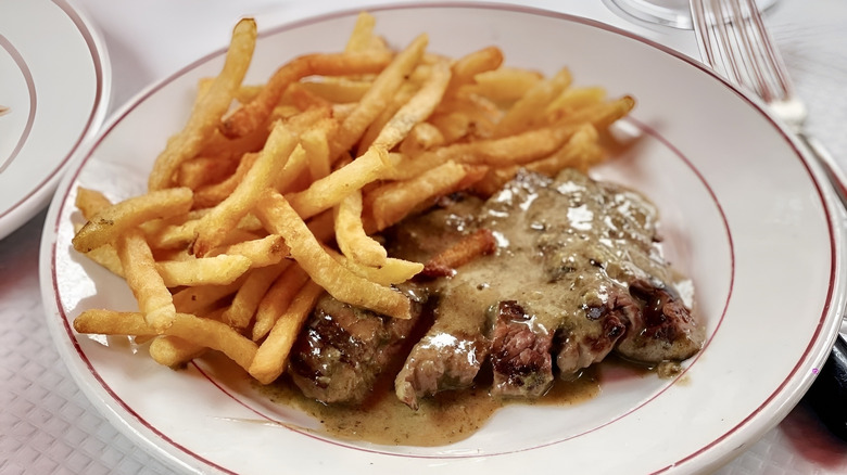 Steak frites on white restaurant plate with fork