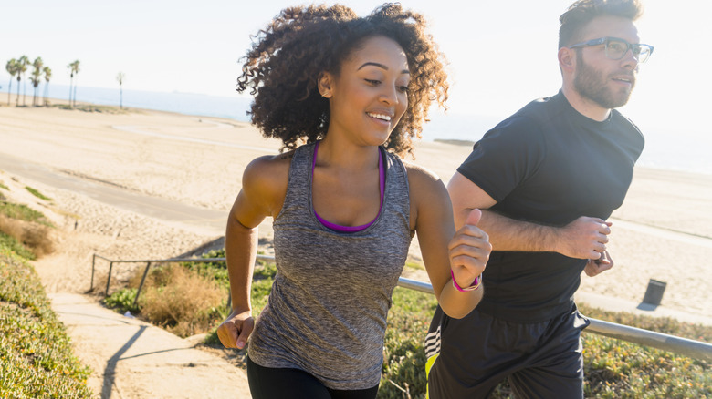 Couple jogs along the beach on a sunny day