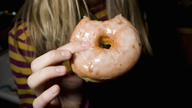 Person holding donut with bite taken out of it