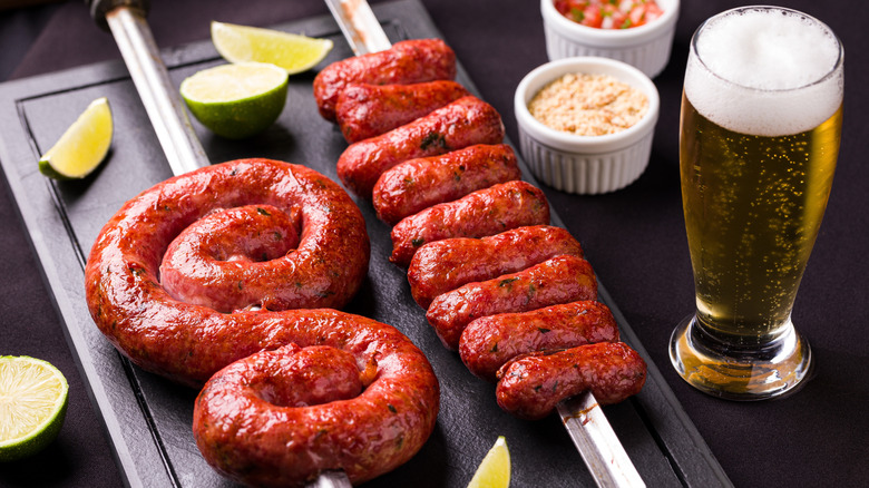 A tray with skewers of Brazilian sausages and beer