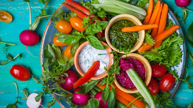 A crudités platter including carrots, tomatoes, bell peppers, and cucumbers