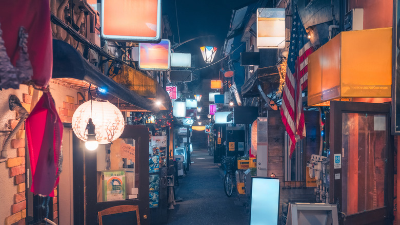 An alleyway in Japan with various izakayas, bars, and restaurants.