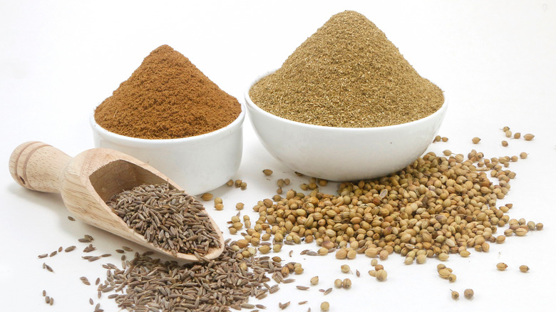 Cumin and coriander seeds and powder in bowls