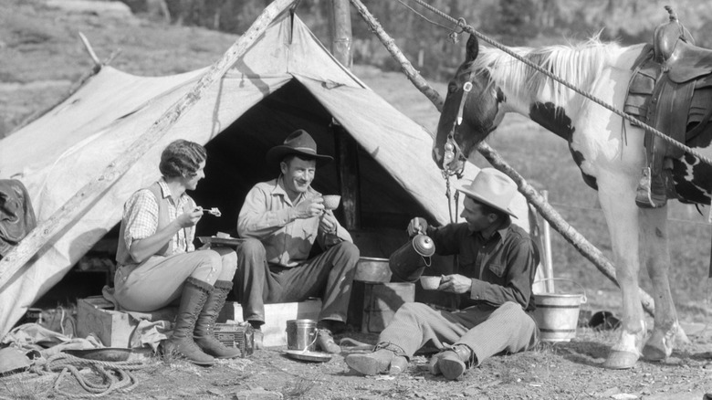 Black and white picture of cowboys and lady drinking coffee