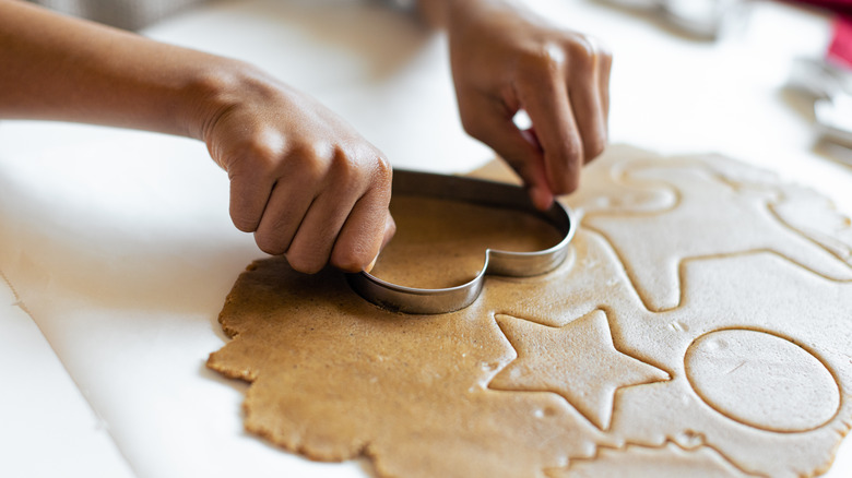 pressing cookie cutters into gingerbread dough