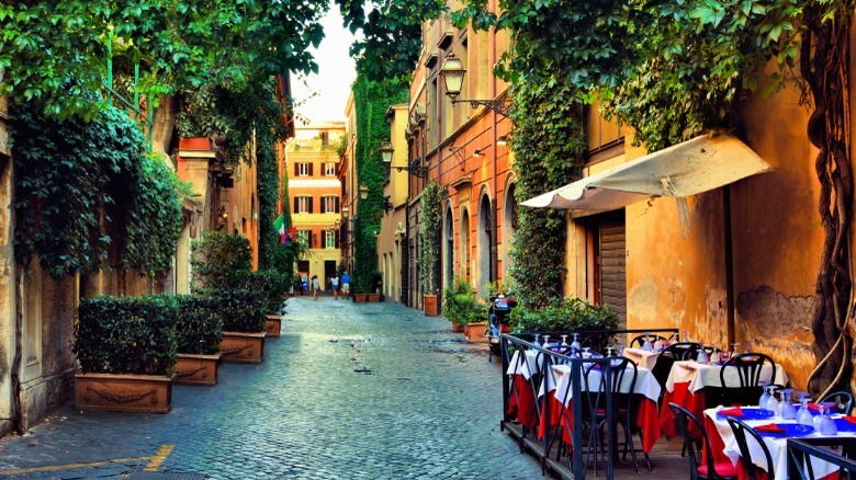 Street in Italy with restaurant tables on the right side 