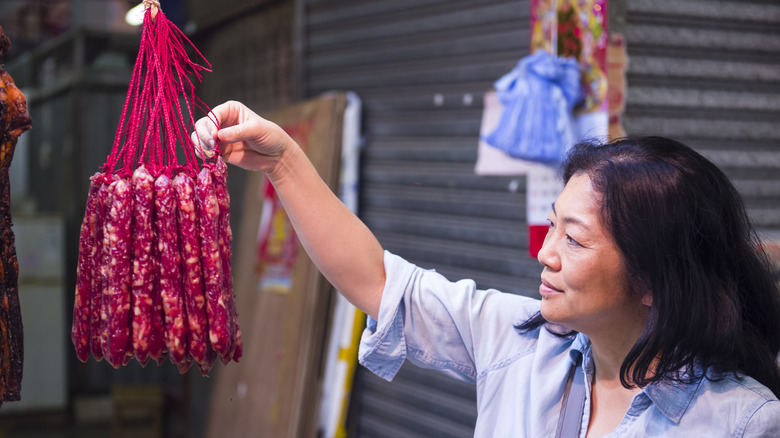 Woman inspecting strings of lap cheong links outdoors