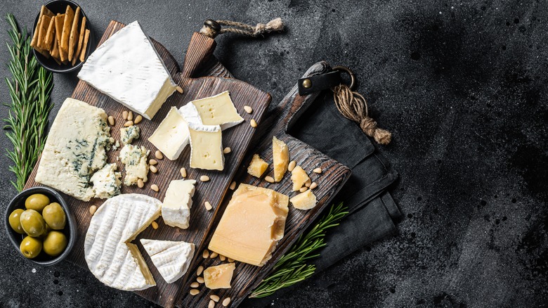 cheese on a wooden board, herbs, ramekin of crackers, ramekin of olives