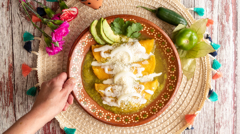 Platter of green enchiladas with avocado and cilantro