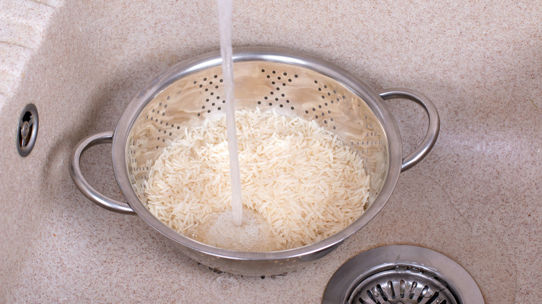 a colander of rice being rinsed in a sink