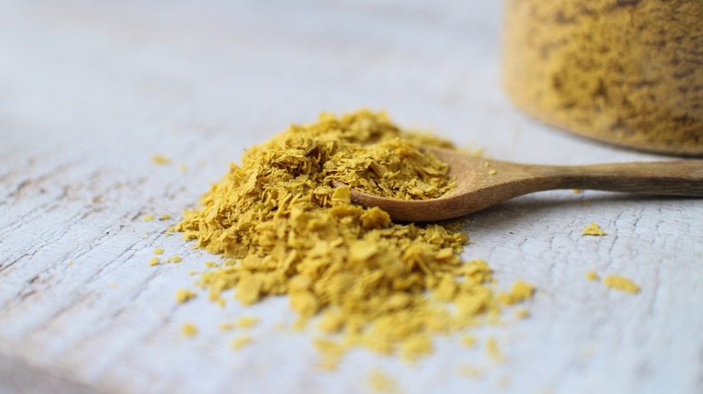 Nutritional yeast on a spoon and scattered on table