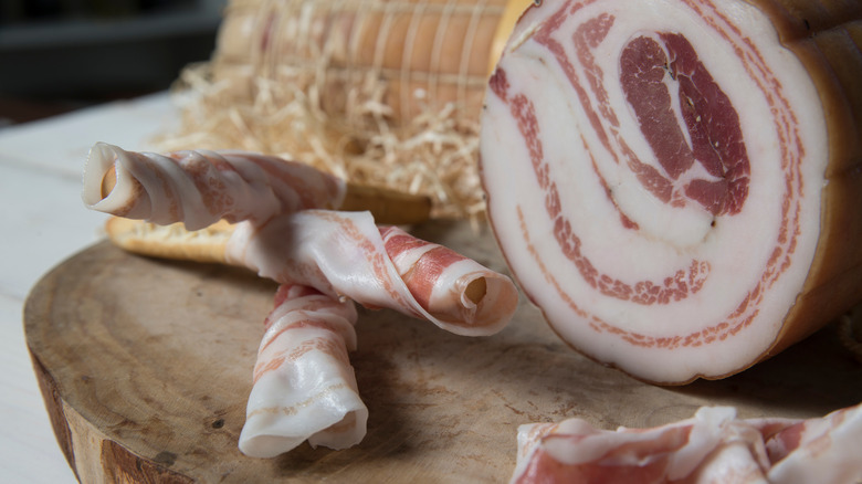 pancetta with rolled slices on wood board