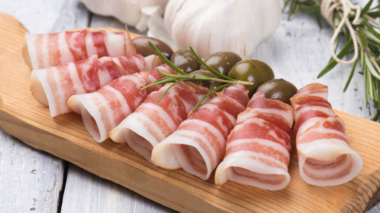 pancetta with rolled slices on wood board
