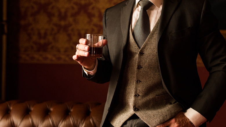 Man in expensive looking suit with glass of bourbon