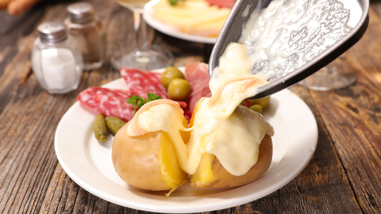 Malted raclette cheese being poured from a mini skillet onto cooked potatoes