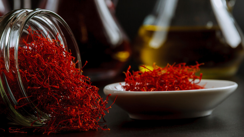 Dried saffron in a glass jar and dish with olive oil