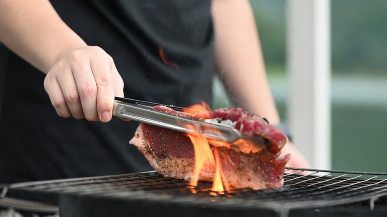 Person cooking a steak on a grill