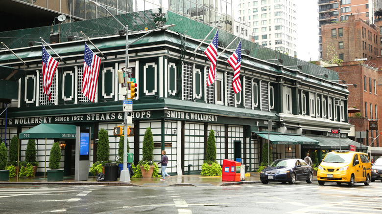 Exterior of Smith & Wollensky Steakhouse in New York City's Midtown East with cars and a taxi cab on the street.